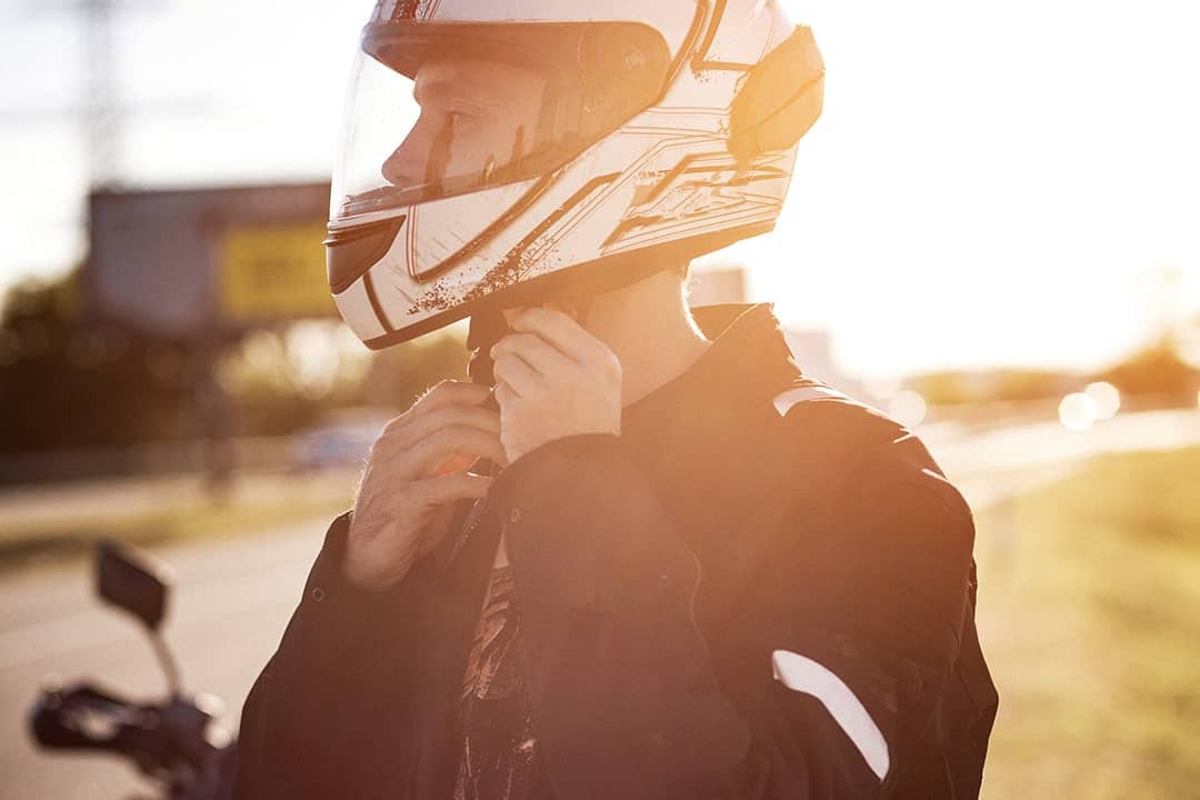 A motorcycle rider fastens his helmet.